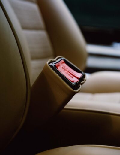 Red seat-belt buckle beside tan seat upholstery