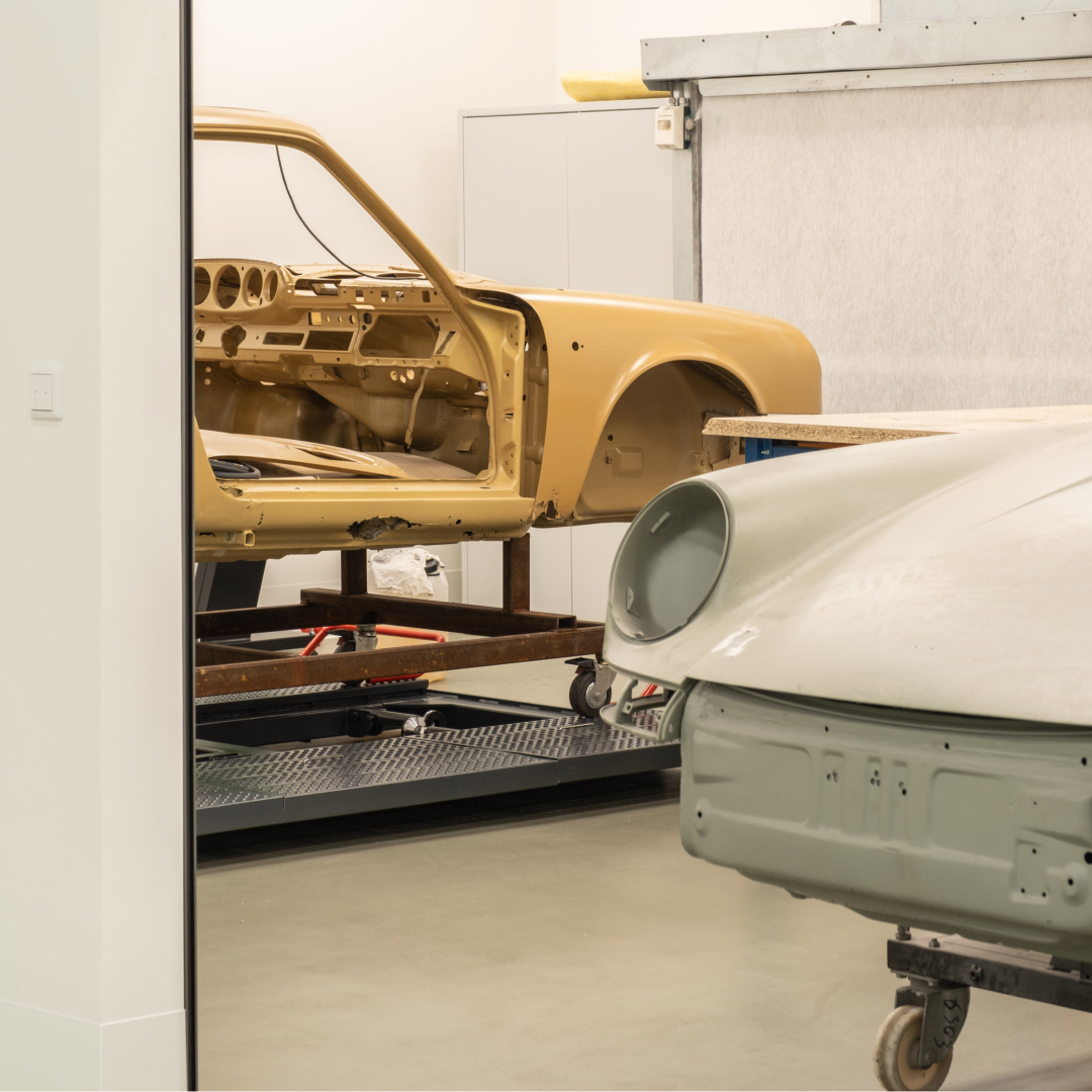 Unfinished vehicle body shells on support frames in the atelier