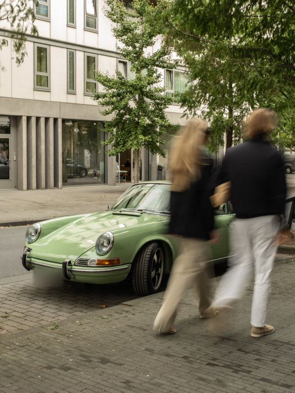 Two people walking towards a green Revolt Electric on a city street