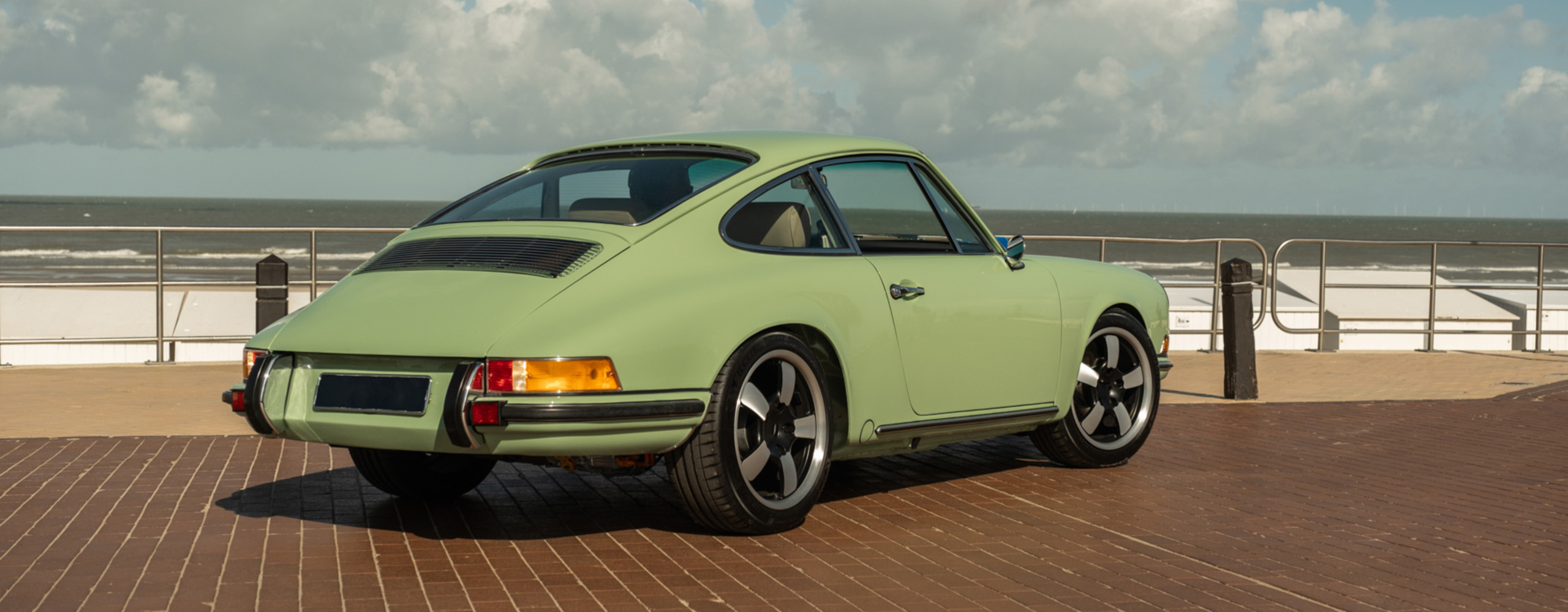 Rear quarter view of a green Revolt Electric beside a beach