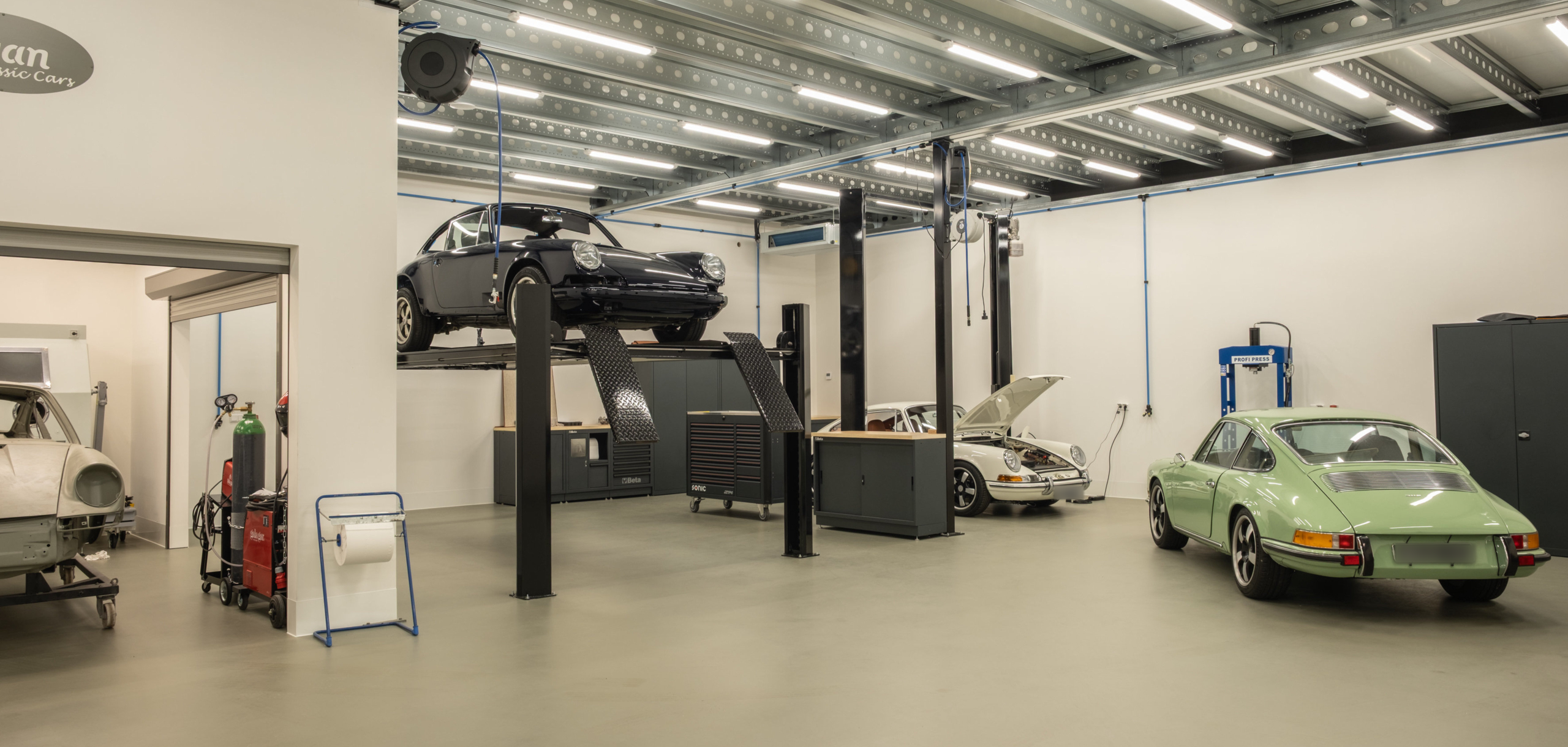 Raised chassis and green car inside the Revolt Classics atelier