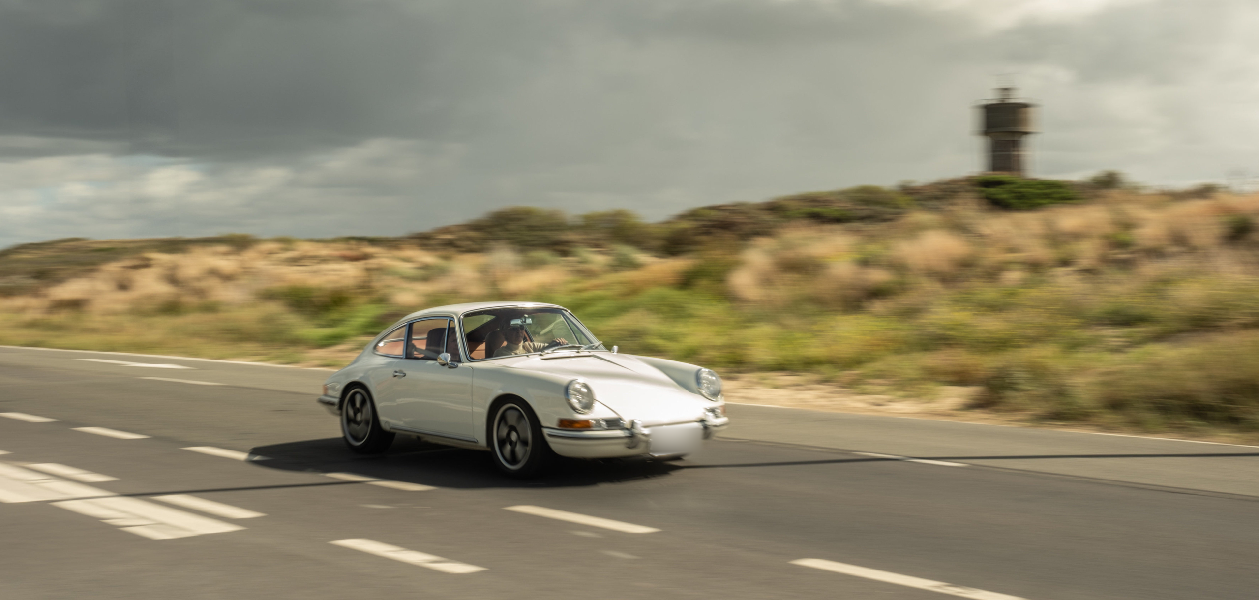 White Revolt Electric driving along a road beside sand dunes